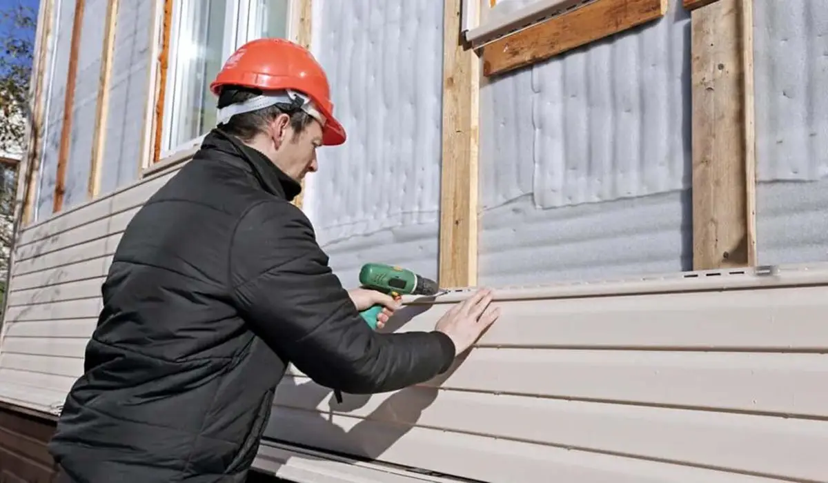a man wearing construction gear and installing siding on a house
