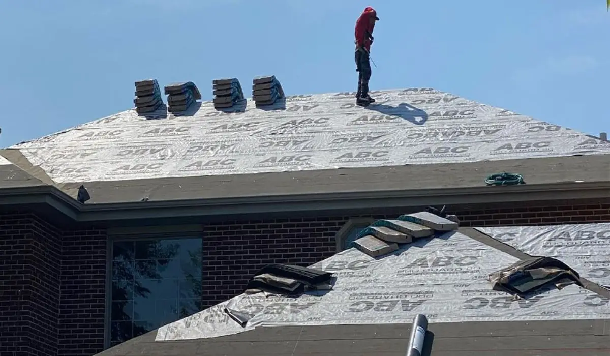 professional roofer standing up at the top of a house to install roof
